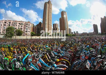 Abandoned bicycles of Mobike (orange), ofo (yellow), Xiaoming Danche, or Xiaoming Bike (blue), and other Chinese bike-sharing services are lined up at Stock Photo