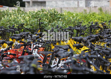 Abandoned bicycles of Mobike (orange), ofo (yellow), Xiaoming Danche, or Xiaoming Bike (blue), and other Chinese bike-sharing services covered by plan Stock Photo