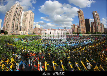 Abandoned bicycles of Mobike (orange), ofo (yellow), Xiaoming Danche, or Xiaoming Bike (blue), and other Chinese bike-sharing services covered by plan Stock Photo