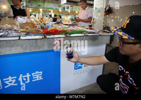 --FILE--A Chinese customer scans a QR code via mobile payment service Alipay of Alibaba Group on his smartphone to pay for his purchase at a free mark Stock Photo