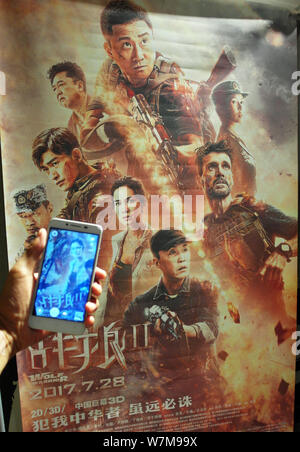 A Chinese filmgoer takes photos of a poster of the Chinese action movie "Wolf Warriors 2" directed by Wu Jing at a cinema in Yichang city, central Chi Stock Photo