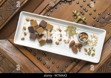 Overhead shot of different types of nuts and square-shaped nuts on a wooden decorative surface Stock Photo