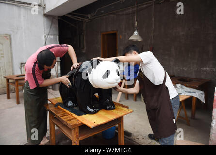 --FILE--Chinese artists paint one of the two life-size lacquerware giant pandas in Chengdu city, southwest China's Sichuan province, 26 May 2017.   Ch Stock Photo