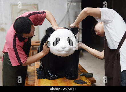 --FILE--Chinese artists paint one of the two life-size lacquerware giant pandas in Chengdu city, southwest China's Sichuan province, 26 May 2017.   Ch Stock Photo