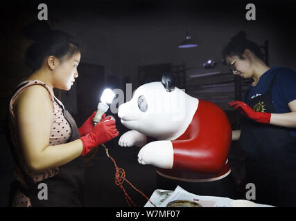 --FILE--Chinese artists paint one of the two life-size lacquerware giant pandas in Chengdu city, southwest China's Sichuan province, 31 May 2017.   Ch Stock Photo