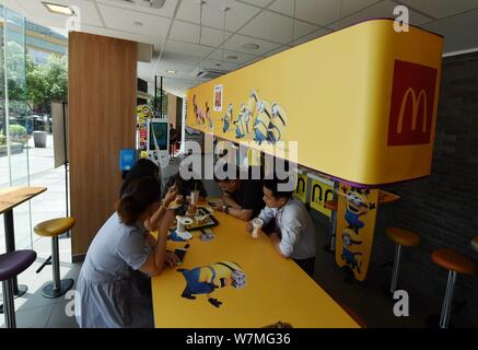 Customers eat food at a Minions-themed fastfood restaurant of McDonald's in Hangzhou city, east China's Zhejiang province, 4 July 2017.   Universal Pi Stock Photo