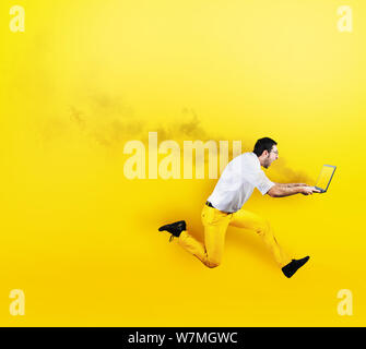 Businessman runs with laptop on fire in hand. Yellow style Stock Photo