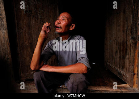 An old man sitting in front of his house with arm deformed by Hundred-pace pitviper snake bite (Deinagkistrodon acutus) Fanjingshan National Nature Reserve, Guizhou Province, China, June 2008. Stock Photo