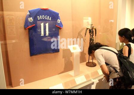 Visitors look at the fake English football jersey bearing the name of  Didier Drogba, an Ivory Coast footballer who grew up in France, displayed durin Stock Photo