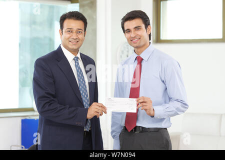 Businessman giving salary cheque to his employee Stock Photo