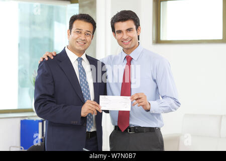 Businessman giving salary cheque to his employee Stock Photo