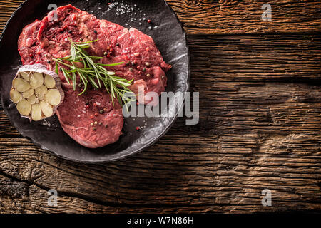 Beef meeat Rib-Eye steak wit rosemary salt and pepper on black plate Stock Photo