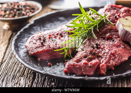 Beef meeat Rib-Eye steak wit rosemary salt and pepper on black plate Stock Photo