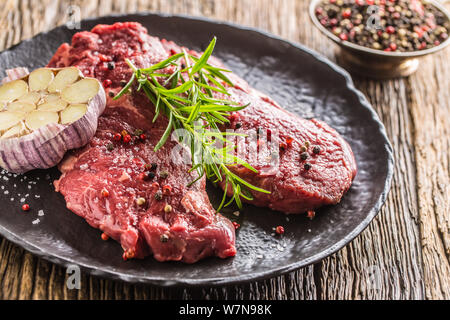 Beef meeat Rib-Eye steak wit rosemary salt and pepper on black plate Stock Photo