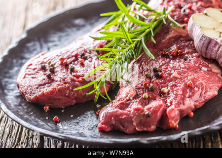 Beef meeat Rib-Eye steak wit rosemary salt and pepper on black plate Stock Photo
