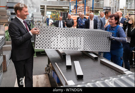 Heinsdorfergrund, Germany. 07th Aug, 2019. Michael Kretschmer (CDU, l), Prime Minister of Saxony, helps Elke Wentsche, an employee of Thermofin GmbH, to assemble a heat exchanger during a tour of the production facility. Thermofin is an internationally active company in the production of components for refrigeration and air conditioning. Credit: Robert Michael/dpa-Zentralbild/dpa/Alamy Live News Stock Photo