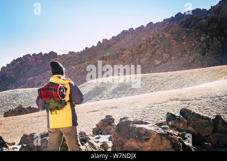 Outdoor leisure activity people with standing man and backpack hiking the mountains alone - travel and discover exploring the workd concept - back vie Stock Photo