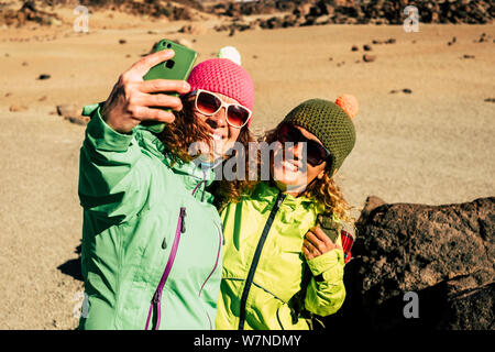 People have fun in outdoor leisure sport activity at the mountain - couple of cheerful women with backpack on the mountain walking and doing trekking Stock Photo