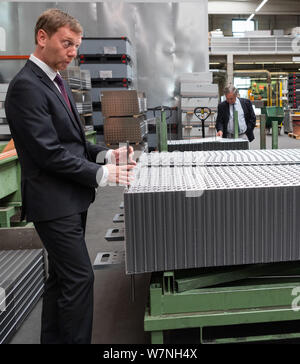 Heinsdorfergrund, Germany. 07th Aug, 2019. Michael Kretschmer (CDU), Prime Minister of Saxony, helps to assemble a heat exchanger during a tour of Thermofin GmbH's production facilities. Thermofin is an internationally active company in the production of components for refrigeration and air conditioning. Credit: Robert Michael/dpa-Zentralbild/dpa/Alamy Live News Stock Photo