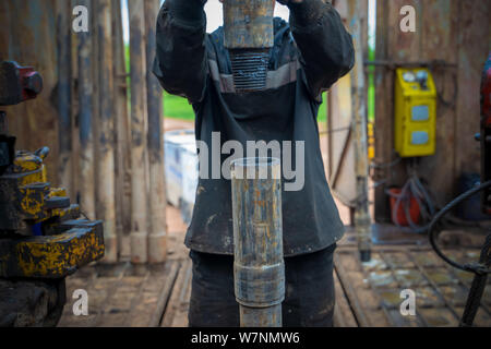 Offshore oil rig worker prepare tool and equipment for perforation oil and gas well at wellhead platform. Making up a drill pipe connection. A view fo Stock Photo