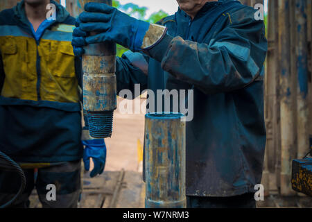 Offshore oil rig worker prepare tool and equipment for perforation oil and gas well at wellhead platform. Making up a drill pipe connection. A view fo Stock Photo