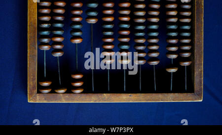 Vintage wooden abacus close up. Counting wooden knuckles. Part of the old end of the abacus on a dark blue background Stock Photo