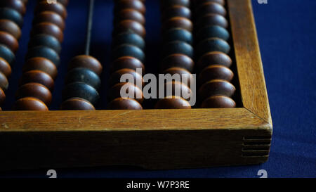 Vintage wooden abacus close up. Counting wooden knuckles. Part of the old end of the abacus on a dark blue background Stock Photo