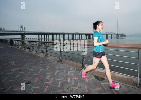 A Chinese running enthusiast jogs along the past the Shenzhen Bay Bridge, also known as the Hong Kong-Shenzhen Western Corridor, in Shenzhen city, sou Stock Photo