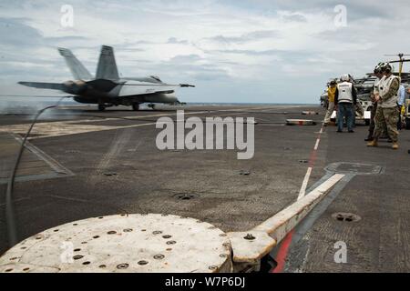 190806-N-CL027-1321 SOUTH CHINA SEA (August 6, 2019) Distinguished visitors observe as an F/A-18E Super Hornet from Strike Fighter Squadron (VFA) 27 lands on the flight deck of the Navy’s forward-deployed aircraft carrier USS Ronald Reagan (CVN 76) during a tour. Maj. Gen. Erickson Gloria, Deputy Chief of Staff, Armed Forces of the Philippines, and Mr. Toby Purisima, the Philippines’ Assistant Secretary of Civil Defense, were among notable visitors to the ship. The enduring U.S.-Philippine relationship is a staple of peace and security in a free and open Indo-Pacific Region. Ronald Reagan, the Stock Photo