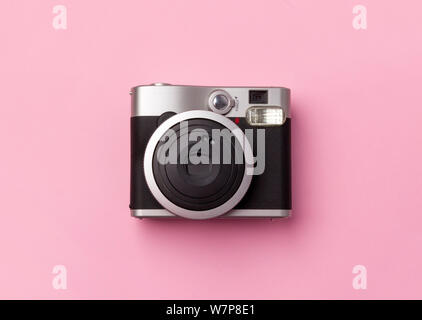 Vintage instant camera at pastel pink background. Trendy film photo cam top view Stock Photo
