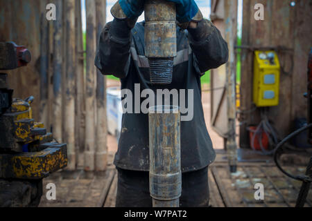 Offshore oil rig worker prepare tool and equipment for perforation oil and gas well at wellhead platform. Making up a drill pipe connection. A view fo Stock Photo