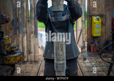 Offshore oil rig worker prepare tool and equipment for perforation oil and gas well at wellhead platform. Making up a drill pipe connection. A view fo Stock Photo