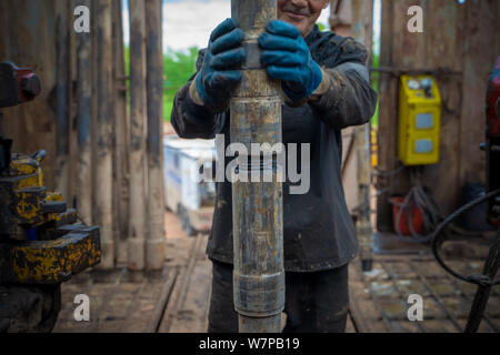 Offshore oil rig worker prepare tool and equipment for perforation oil and gas well at wellhead platform. Making up a drill pipe connection. A view fo Stock Photo