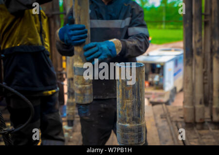 Offshore oil rig worker prepare tool and equipment for perforation oil and gas well at wellhead platform. Making up a drill pipe connection. A view fo Stock Photo