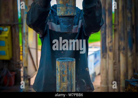 Offshore oil rig worker prepare tool and equipment for perforation oil and gas well at wellhead platform. Making up a drill pipe connection. A view fo Stock Photo