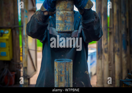 Offshore oil rig worker prepare tool and equipment for perforation oil and gas well at wellhead platform. Making up a drill pipe connection. A view fo Stock Photo