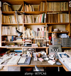Cluttered desk with shelving Stock Photo