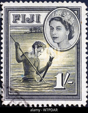 Nocturnal fisherman on vintage postage stamp of Fiji Stock Photo