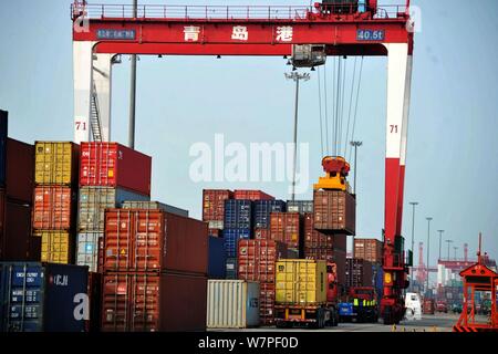 A crane vehicle lifts containers to be shipped abroad from trucks on a quay at the Port of Qingdao in Qingdao city, east China's Shandong province, 7 Stock Photo