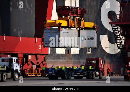 A crane vehicle lifts containers to be shipped abroad from trucks on a quay at the Port of Qingdao in Qingdao city, east China's Shandong province, 7 Stock Photo