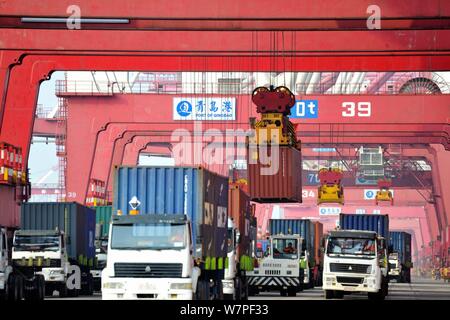 A crane vehicle lifts containers to be shipped abroad from trucks on a quay at the Port of Qingdao in Qingdao city, east China's Shandong province, 7 Stock Photo