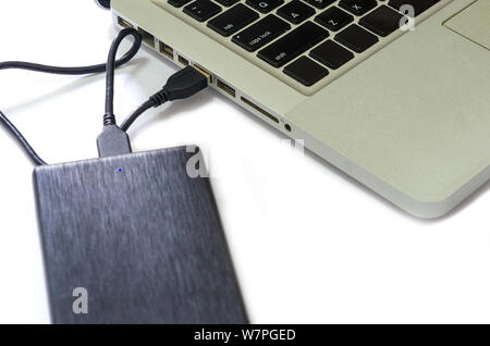External hard drive connect to laptop computer on the white background. Stock Photo