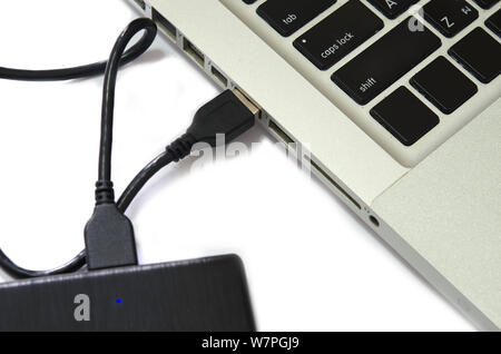 External hard drive connect to laptop computer on the white background. Stock Photo