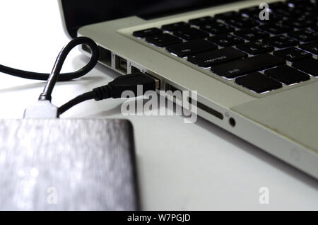 External hard drive connect to laptop computer on the white background. Stock Photo
