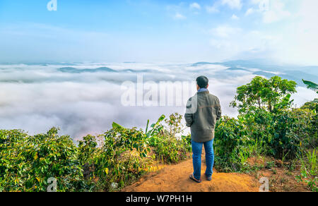 Silhouette of man standing on a high hill scenic rural hometown in the morning valley fog shrouded mountains looming large undulating scenic spot Stock Photo
