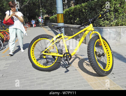 A pedestrian takes photos of a fatbike with oversized tires, also called fat bike or fat-tire bike, of Chinese bike-sharing service ofo, in Beijing, C Stock Photo