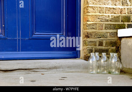 Five empty glass milk bottles on doorstep, Highbury, London Borough of Islington, England, UK Stock Photo