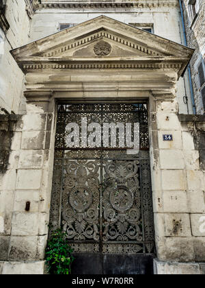 Old gateway and decorative cast iron gates to abandoned city centre house, Chatellerault, France. Stock Photo