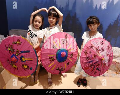 Chinese children pose with oil paper umbrellas at the stuidio of Yu Wanlun, the seventh generation successor of Luzhou's oil paper umbrella, in Hangzh Stock Photo