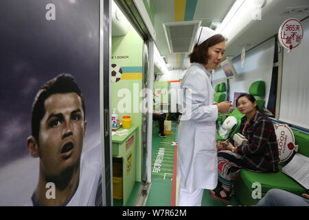 A nurse and a blood donor are seen in a mobile blood donation vehicle endorsed by Portuguese football star Cristiano Ronaldo on a street in Shanghai, Stock Photo